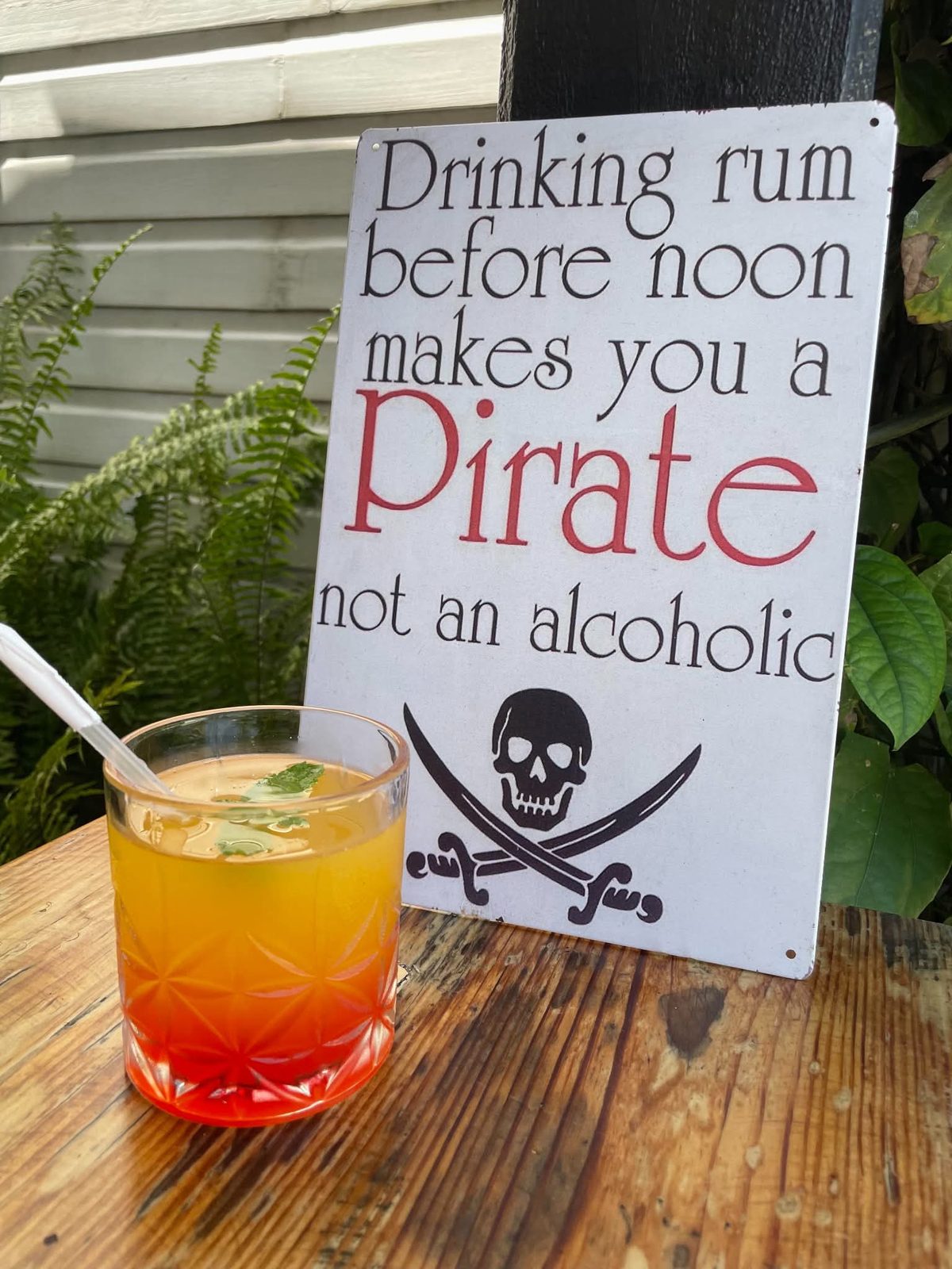 Orange cocktail beside a pirate sign: Drinking rum before noon makes you a pirate
